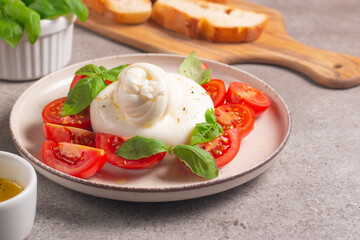 Traditional Italian burrata cheese with salad of delicious cherry tomato, basil leaves and olive oil.