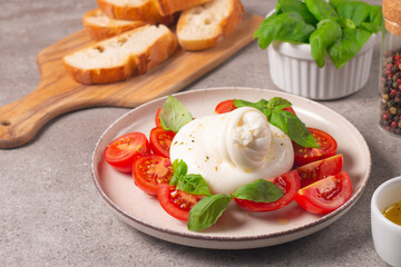 Traditional Italian burrata cheese with salad of delicious cherry tomato, basil leaves and olive oil.