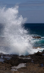 Gran Canaria, north west coast around natural swimming pools Salinas de Agaete, waves breaking against old eroded dark lava platform