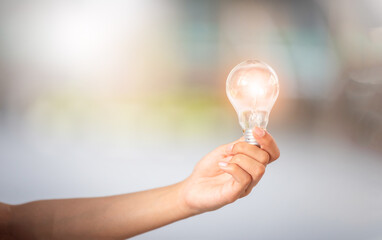 Hand hold light bulb on green bokeh background.