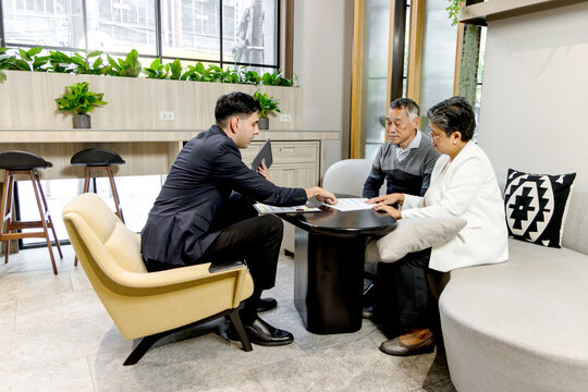 Financial advisor advising retirement advice to senior Asian couple. Happy mature couple discussing retirement planning with advisor. Elderly customers meeting with agent to sign insurance agreement.