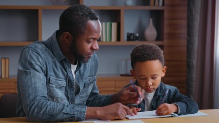 African American family dad assists son with learning teamwork lovely schoolboy with father writing homework at home child kid boy with parent tutor tutoring distant education concentration study - Powered by Adobe