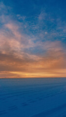Winter sunset glows across a vast snowy horizon.
