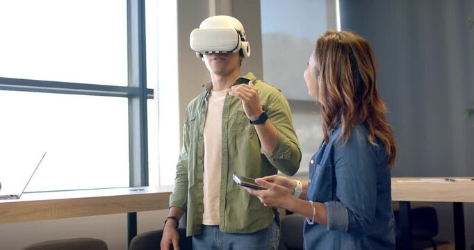 Asian man receiving VR headset for training from instructor, exploring interface in training room