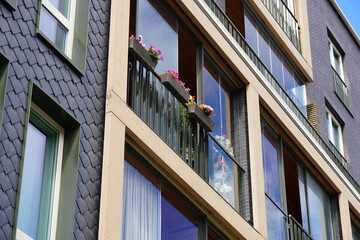 Modern apartment building with balconies featuring colorful flowers in a vibrant urban setting during daylight hours