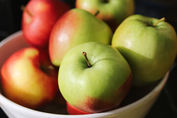 Fresh apples in bowl. Green and red apples in kitchen interior. Healthy fruit for diet and lifestyle. Organic apples with natural vitamins. Seasonal harvest concept with nutrition.