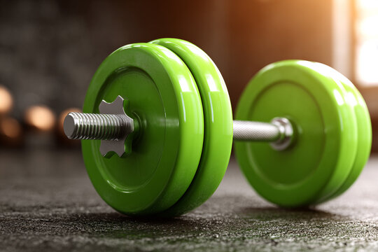 Green dumbbell on dark floor gym fitness workout weightlifting exercise strength training
