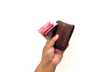 A hand presents a brown leather wallet filled with paper currency. Represents wealth, finance, and spending power in business.