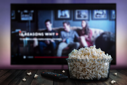 Video streaming app on tv screen behind a bowl of popcorn and a remote control.	