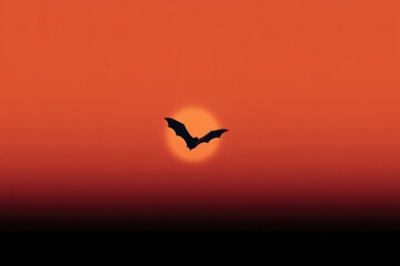 Fototapeta premium Silhouette of bat flying against vibrant sunset sky creates dram