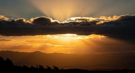 Golden Rays of Light Shine Through Dramatic Clouds Over Mountain Landscape