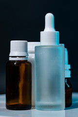 A studio shot featuring an assortment of pharmaceutical glass and plastic bottles, illuminated by dim blue lighting against a dark background, showcasing various healthcare and wellness products