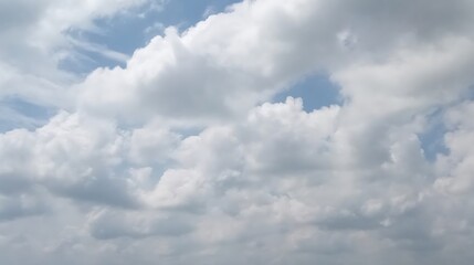 Fluffy white clouds floating across a pale blue summer sky