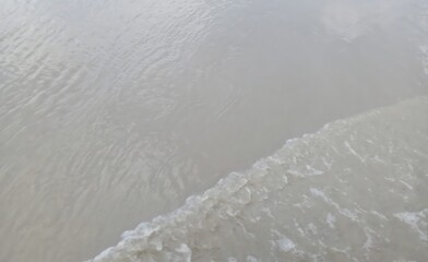 Overcast day at the beach with cool toned water flowing onward