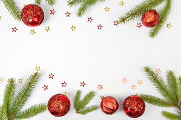 Christmas card made of green Christmas tree branches, red decorative balls and glitter stars on gray background with space for text and greetings. Flat lay, copy space