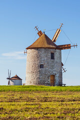 Rustic stone windmill in a grassy field