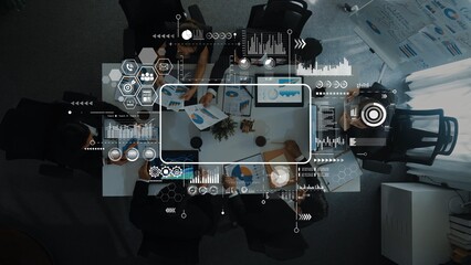 Aerial view of a diverse business team engaged in a collaborative meeting, analyzing data and discussing strategies. Visual digital elements enhance the workspace atmosphere. Raster