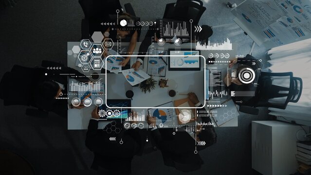 Aerial view of a diverse business team engaged in a collaborative meeting, analyzing data and discussing strategies. Visual digital elements enhance the workspace atmosphere. Raster