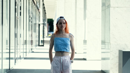 Portrait of a teenage girl with red hair standing near columns at the entrance to a business center