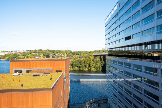 Reflections of glass façades and modern apartment buildings with green roof in Liljeholmen Stockholm, Scandinavian waterfront architecture highlighting clarity and sustainable housing design