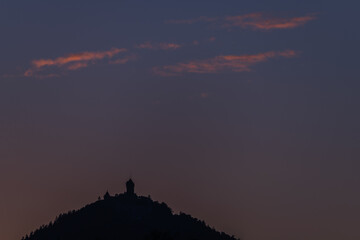 Sunset on hill with castle in silhouette on horizon