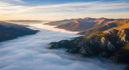 Naklejka premium Breathtaking aerial view of a majestic mountain landscape at sunrise, with a vast sea of clouds filling the valley below and golden light illuminating the rugged peaks and forested slopes.