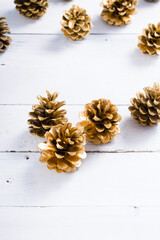 golden pine cones Christmas decoration on white wood table background