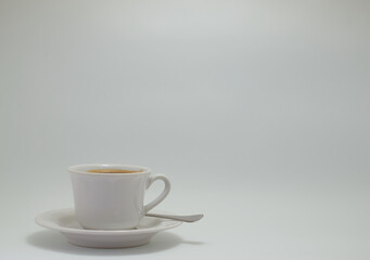 Titulo: Taza de café blanca
Descripción: una taza de café blanca con plato y cucharilla con un fondo blanco.