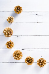 golden pine cones Christmas decoration on white wood table background