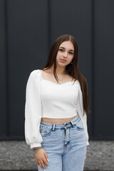 A girl in blue jeans near a metal wall