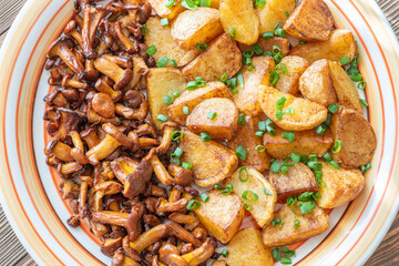 Fried potatoes chanterelle mushrooms seasoned paprika rustic wooden table plate