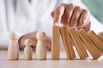 Fototapeta na wymiar Risk. Woman stopping domino effect to protect wooden figures at table, closeup