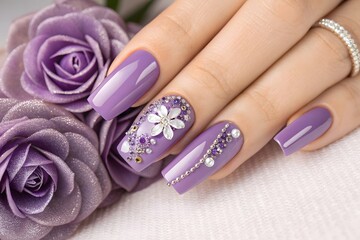 Elegant purple manicure adorned with floral designs and sparkling rhinestones.