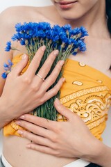 Fototapeta premium Hand with Pearl Ring Holding Blue Cornflowers