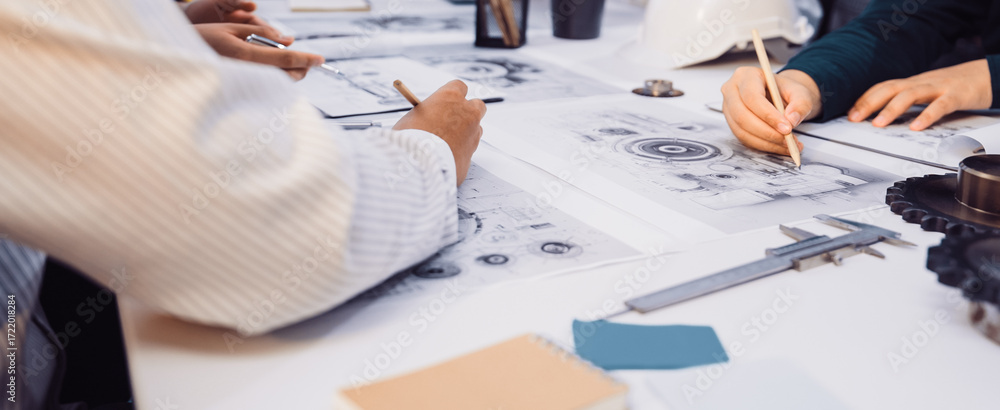Aufkleber a focused group of engineers collaborates on technical drawings, utilizing tools and notebooks on a 