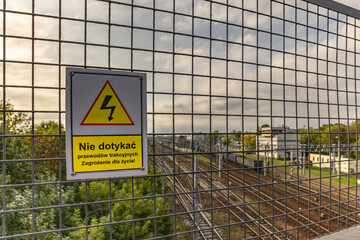 High voltage warning sign, warning sign hanging above the railway tracks Poland