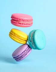 Colorful macarons float mid-air on pastel blue background. Pink, yellow, purple, and turquoise cookies in soft light. Minimal, playful, elegant dessert display.