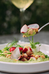 Spoon lifting healthy green appetizer with chickpeas and radish