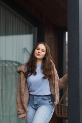 A girl on the terrace in blue jeans and a warm jacket