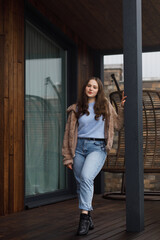 A girl on the terrace in blue jeans and a warm jacket