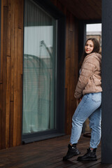 A girl on the terrace in blue jeans and a warm jacket