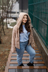 A girl in blue jeans and a warm jacket outside in winter