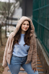 A girl in blue jeans and a warm jacket outside in winter