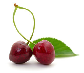 Two sweet cherries with green leaf isolated on white background
