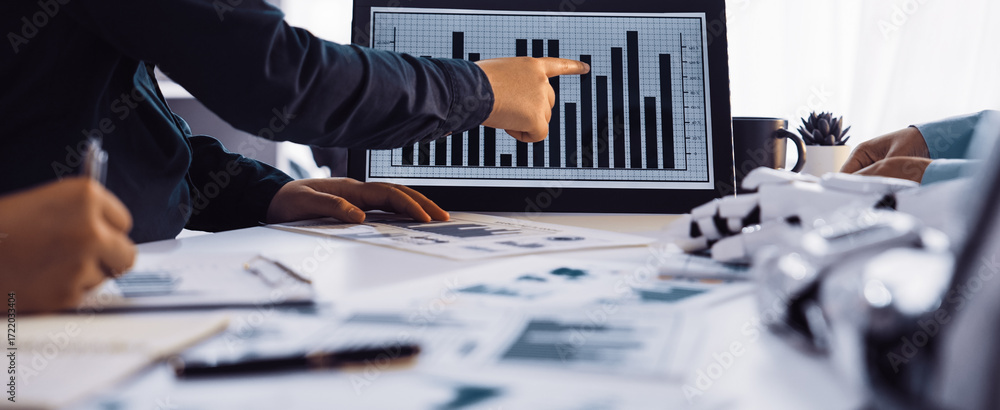 Poster a professional business team collaborates in a modern office, analyzing graphs and charts displayed 