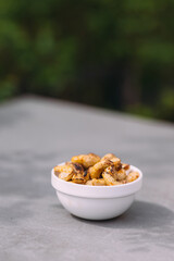 Roasted cashews in a white bowl with green background