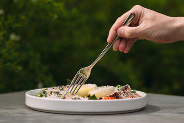 Hand using a fork eating healthy food outdoors