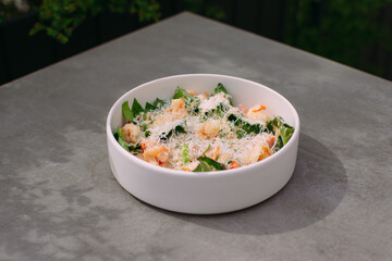White bowl of pasta with shrimp and parmesan cheese