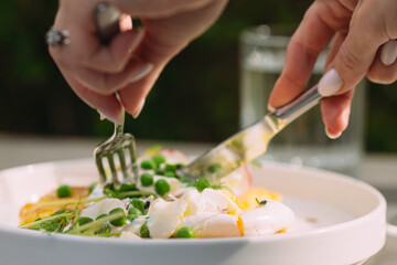 Woman cutting poached egg with peas and sprouts