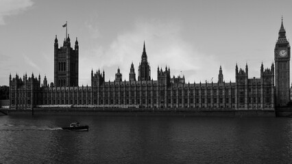 Westminster Abbey in a retro-style black and white photo, with a boat cruising up the River Thames, an iconic Anglican church anchoring the architectural landscape of London’s City of Westminster.